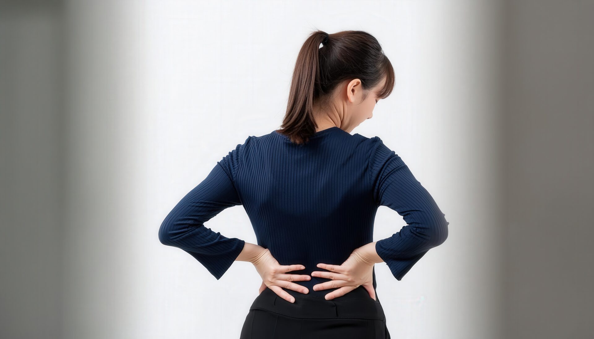 腰を支える女性の後ろ姿