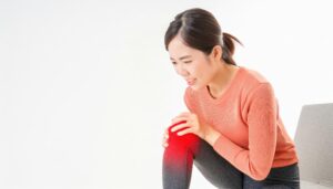 膝を押さえて痛みに耐える女性