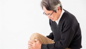 膝を抱える高齢男性