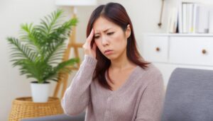 リビングで頭痛を感じる女性