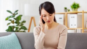 リビングで頭痛に苦しむ高齢女性