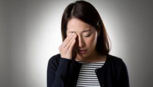 目の疲れで目を押さえる人(2)