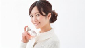白いニットの女性が香水を胸元に添え笑顔