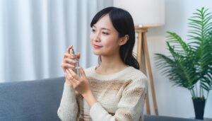 黒髪の女性が香水を見つめるリビングのひととき