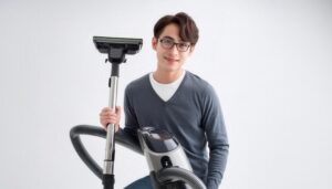 白背景で掃除機を持つメガネ姿の人物