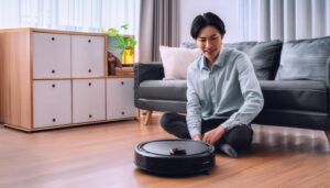 ロボット掃除機を前にして座る人物（青シャツ）