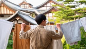 和風建築を背景に洗濯物を干す人物