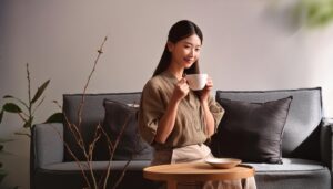 グレーのソファでカップを持つ若い女性