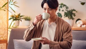リビングでティーカップを飲む若い男性