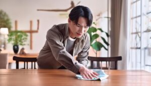 木のテーブルを拭く若い男性