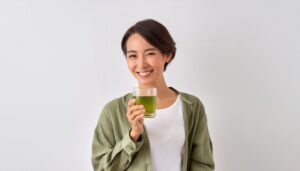 緑色の上着で緑色の飲み物を持つ若い人