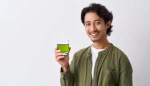 白背景で緑色の飲み物を手にする若い人