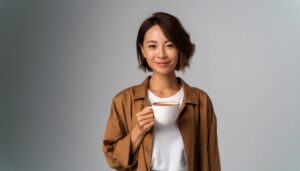 落ち着いた背景で白いカップの茶色い飲み物を持つ若い人