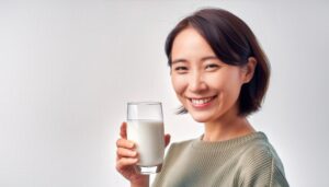 白背景で牛乳を持つ笑顔の若い女性