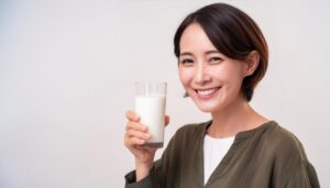 白背景で牛乳を持つ笑顔の若い女性