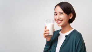 白背景で牛乳を持つ笑顔の若い女性