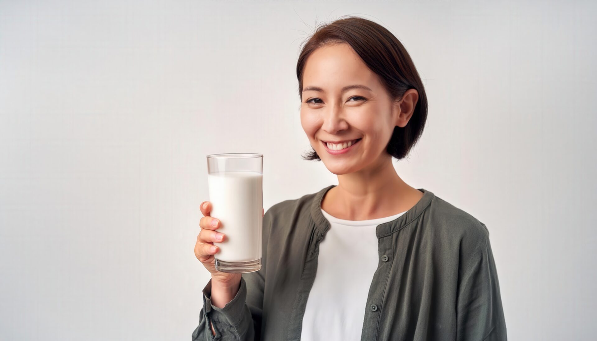 白背景で牛乳を持つ笑顔の若い女性