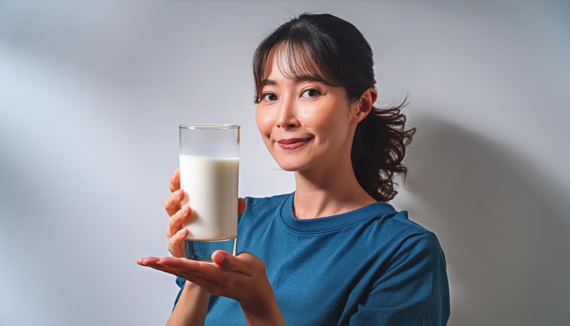白背景で牛乳を持つ笑顔の若い女性