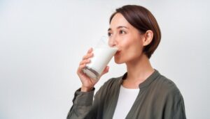 白背景で牛乳を持つ笑顔の若い女性