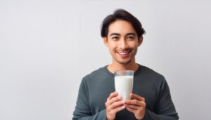 白背景でグラスの牛乳を持つ若い男性