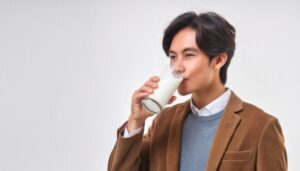 白背景で牛乳を飲む若い男性