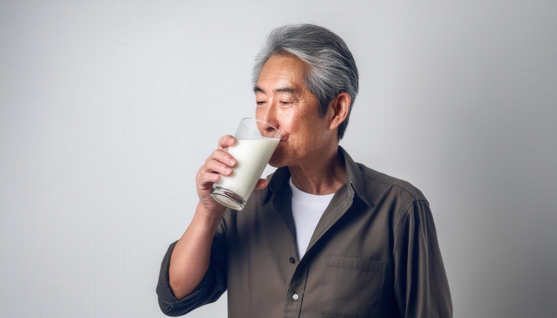 白背景で牛乳を飲む白髪の男性