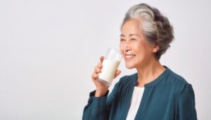 白背景で牛乳を飲むシニア女性（グレー）