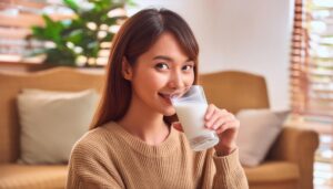 室内で牛乳を飲む若い女性（ベージュのセーター）