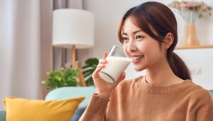 室内で牛乳を飲む若い女性（ポニーテール）