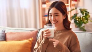 室内で牛乳を飲む若い女性（指差し）