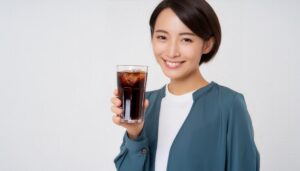 白背景で黒い炭酸飲料を持つ若い女性