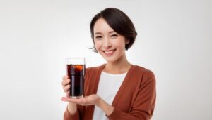 白背景で黒い炭酸飲料のグラスをアピールする若い女性
