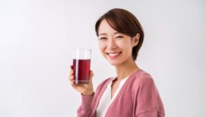 白背景で赤紫色のグレープジュースを手に持つ若い女性