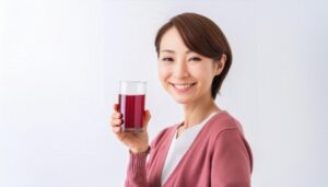 白背景で赤紫色のグレープジュースをアピールする若い女性