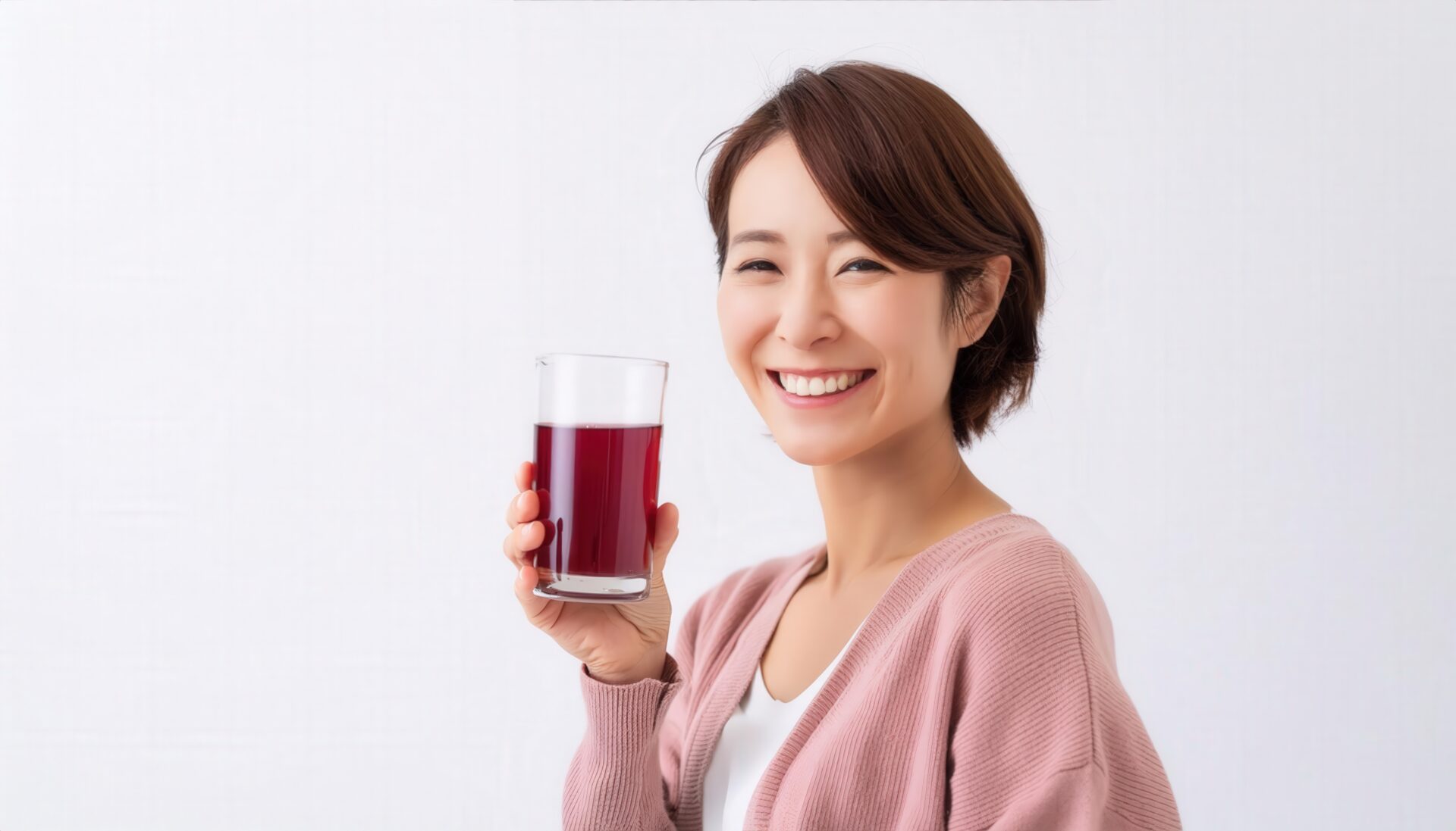 白背景で赤紫色のグレープジュースを手に持つ若い女性