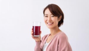 白背景で赤紫色のグレープジュースを手に持つ若い女性