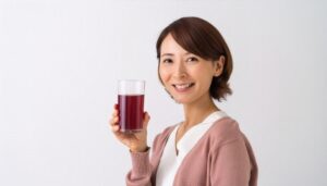 白背景で赤紫色のグレープジュースを手に持つ若い女性