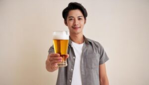 ベージュ背景でビールグラスを差し出す若い男性