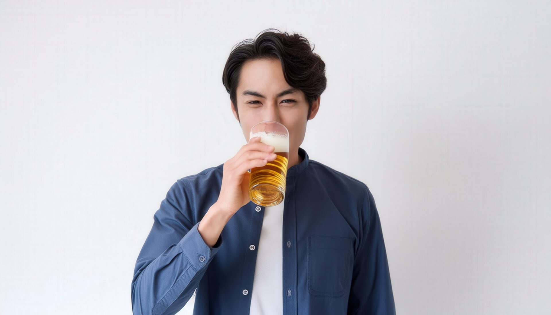 白背景でビールを飲むカジュアルな若い男性