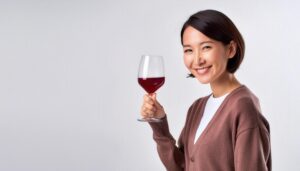 白背景で赤ワインを見せる若い女性