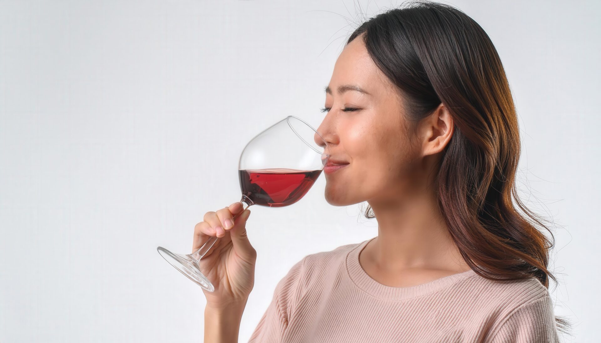 白背景で赤ワインを味わう若い女性