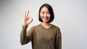 白背景でOKサインをするショートヘアの人物