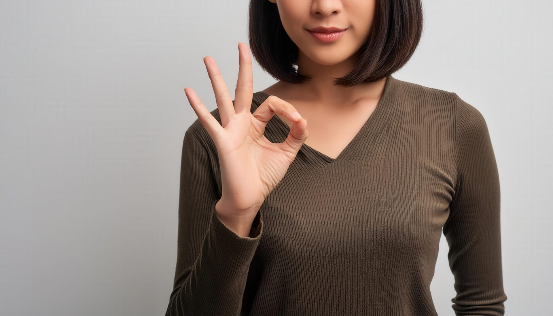 シンプル背景でOKサインをする人物（上半身）