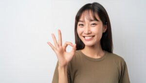 白背景でOKサインをする人物（ロングヘア）