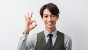 白背景でOKサインをするベスト姿の人物