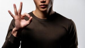 シンプル背景でOKサインをする人物（落ち着いた服装）