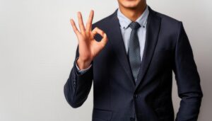 グレー背景でOKサインをするビジネスパーソン