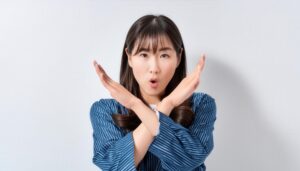 白背景で腕を交差させてバツ印を作る人