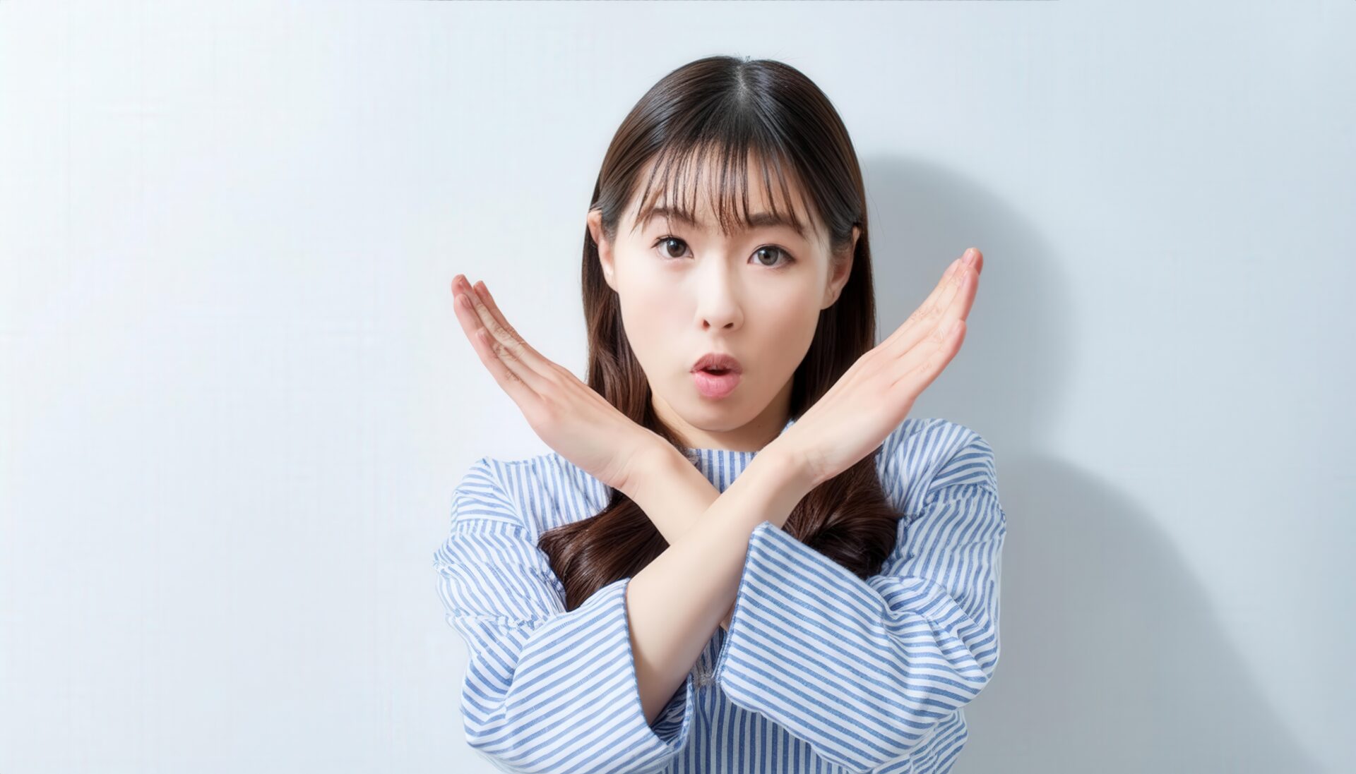 白背景で腕をクロスして拒否を示す人物