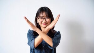 白背景でNGジェスチャーをするメガネをかけた女性